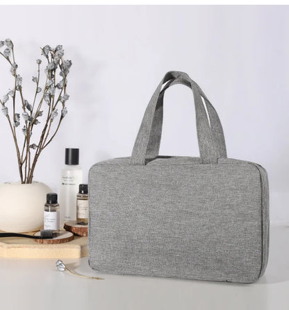 Trousse de toilette de voyage grise au design minimaliste, compacte et résistante pour un rangement élégant des accessoires.