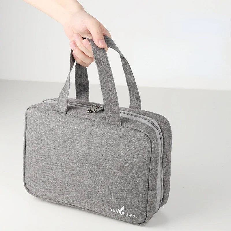 Trousse de toilette de voyage grise pliable avec poignée, compacte et élégante pour organiser ses produits de toilette en déplacement.